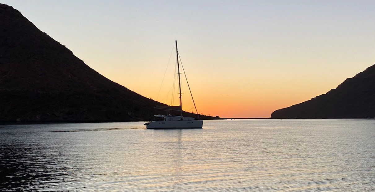 Catamaran in a cove with the sunsetting